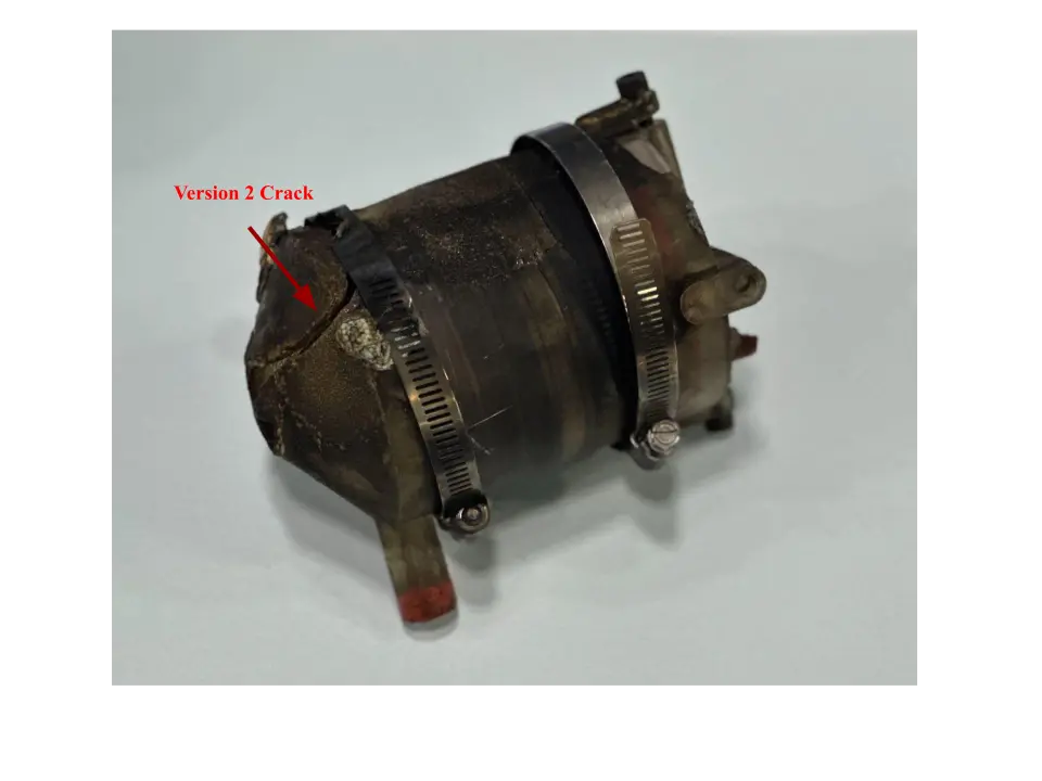 Scorched resin engine on a light surface held by two hose clamps with a red arrow labeled Version 2 Crack pointing at a split near the nozzle